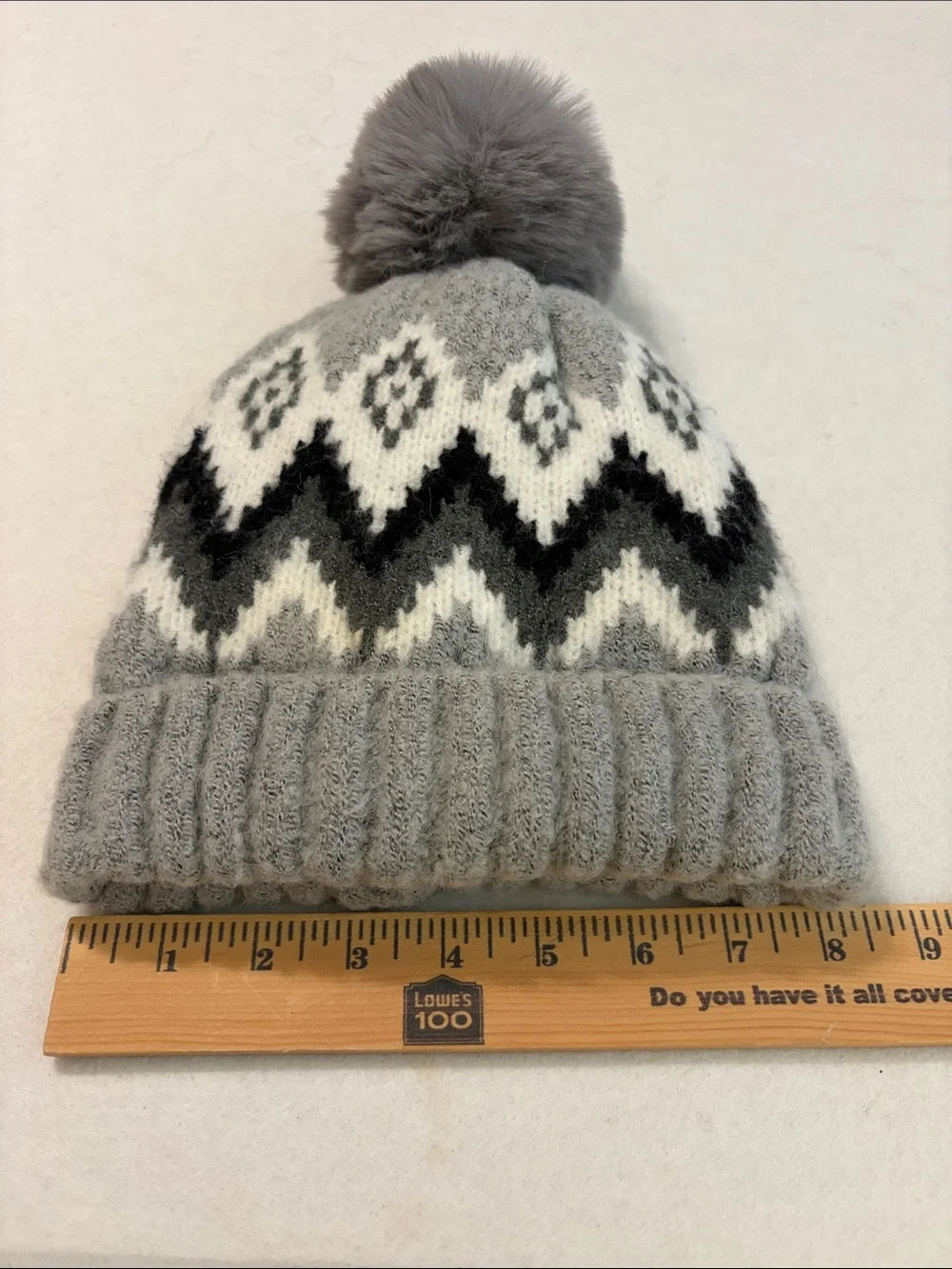 Gray knit beanie with a Fair Isle zigzag pattern and a fuzzy pom-pom on top.